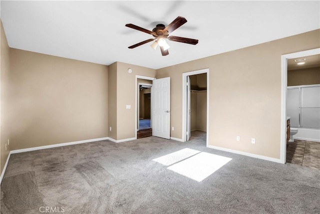 unfurnished bedroom featuring ensuite bathroom, ceiling fan, a spacious closet, carpet floors, and a closet