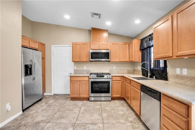 kitchen featuring appliances with stainless steel finishes, light brown cabinetry, lofted ceiling, and sink