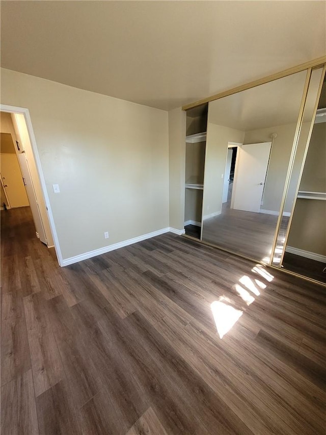 unfurnished bedroom with a closet and dark wood-type flooring