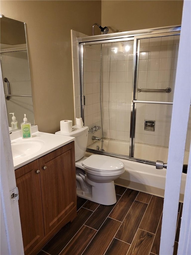 full bathroom featuring vanity, toilet, and bath / shower combo with glass door