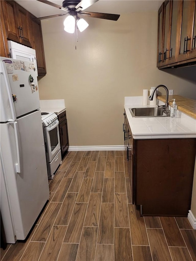 kitchen featuring dark brown cabinets, white appliances, ceiling fan, and sink