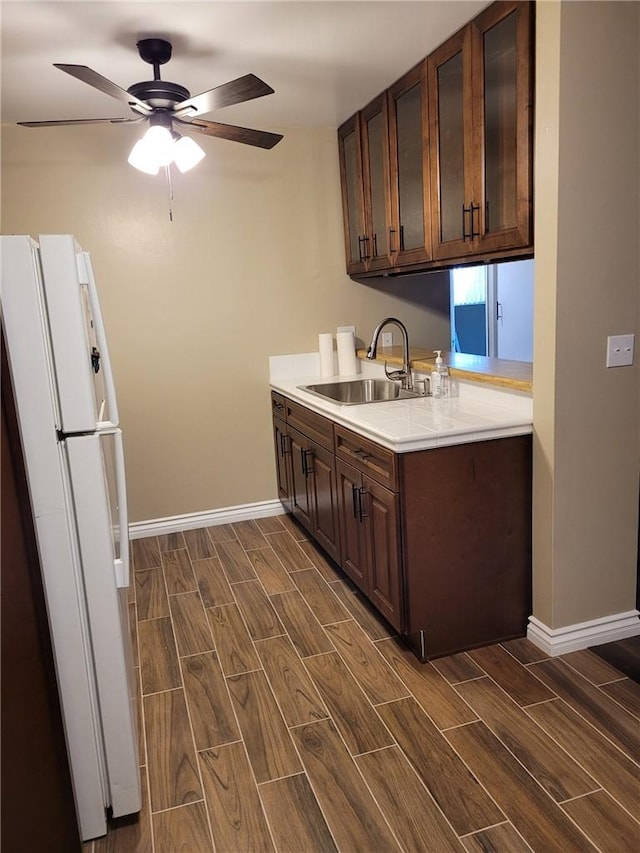 kitchen with sink, ceiling fan, white fridge, dark hardwood / wood-style flooring, and dark brown cabinetry