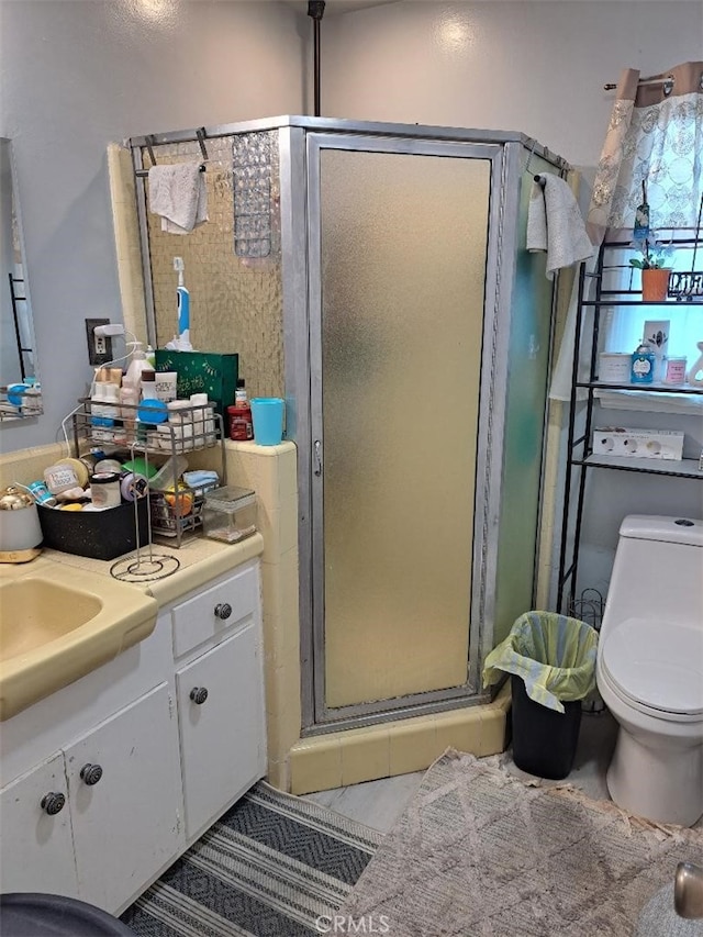 bathroom featuring vanity, toilet, a shower with shower door, and tile patterned flooring