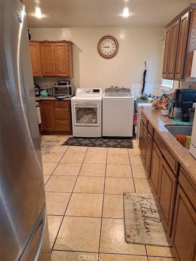 clothes washing area with sink, light tile patterned flooring, and washing machine and dryer