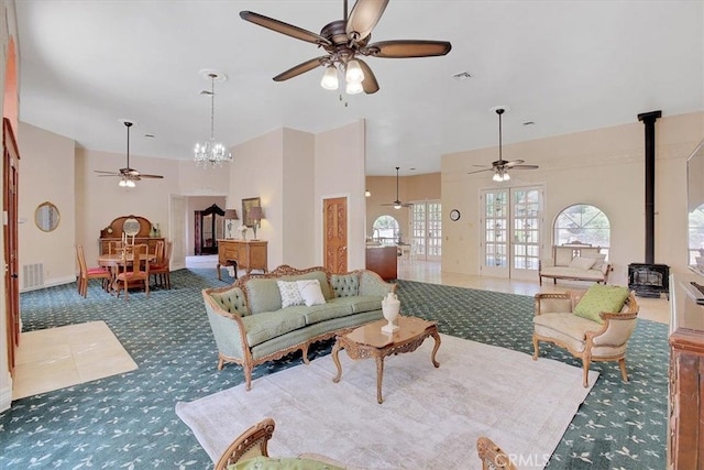 carpeted living room with ceiling fan with notable chandelier and a wood stove