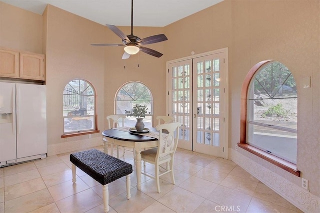 tiled dining room featuring a high ceiling, ceiling fan, and french doors