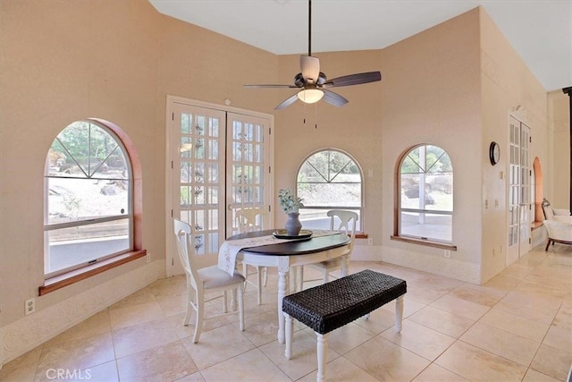 tiled dining room with a towering ceiling, ceiling fan, and plenty of natural light