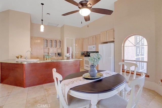 dining area with ceiling fan, light tile patterned floors, sink, and a high ceiling