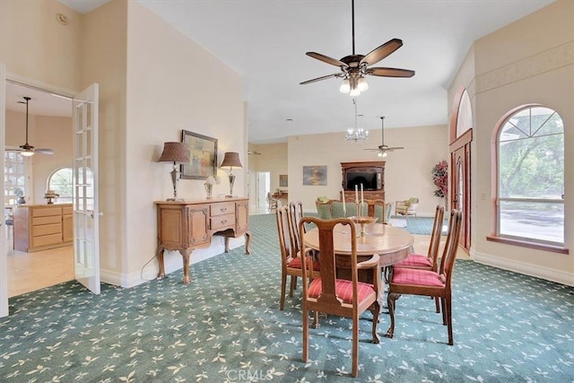 carpeted dining space featuring a towering ceiling and ceiling fan