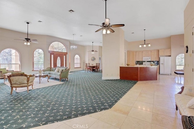 living room with ceiling fan with notable chandelier, a high ceiling, and tile patterned floors