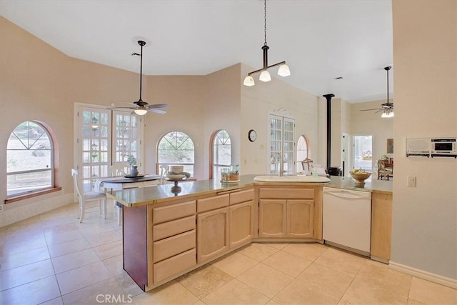 kitchen with ceiling fan, white dishwasher, light tile patterned floors, a wood stove, and light brown cabinetry