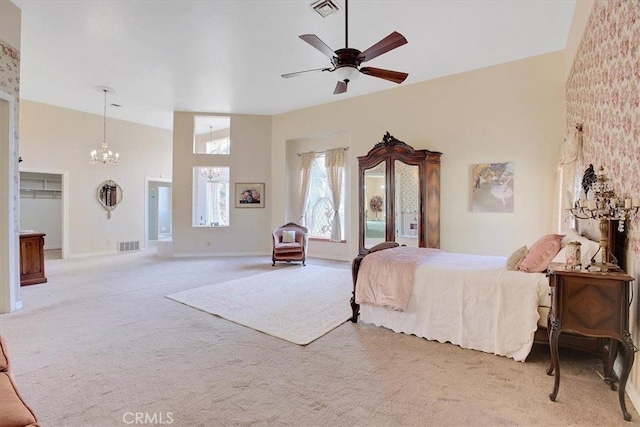 bedroom featuring ceiling fan with notable chandelier, a towering ceiling, and light colored carpet