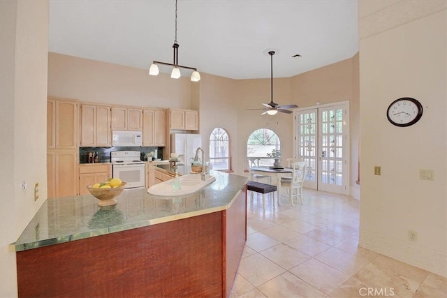 kitchen with ceiling fan, light brown cabinets, white appliances, decorative light fixtures, and a high ceiling