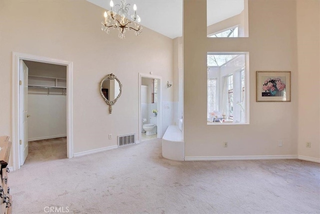 interior space with light carpet, a walk in closet, ensuite bathroom, and an inviting chandelier