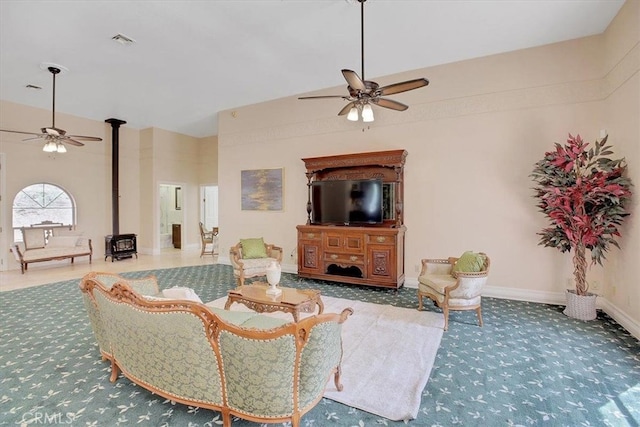 carpeted living room featuring ceiling fan and a wood stove