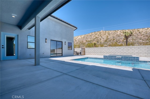 view of pool with a patio, a mountain view, pool water feature, and an in ground hot tub