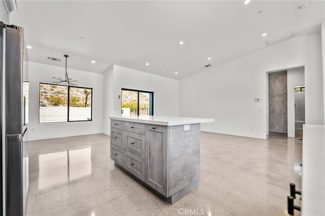 kitchen featuring stainless steel refrigerator, decorative light fixtures, a kitchen island, and gray cabinets