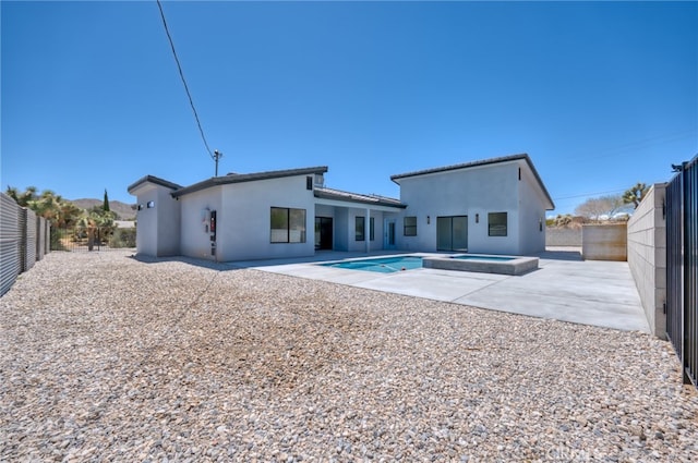 back of house featuring an in ground hot tub and a patio