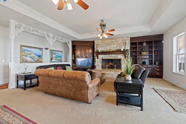 carpeted living room featuring a fireplace, a tray ceiling, ceiling fan, and ornamental molding