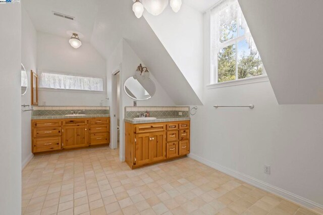 bathroom featuring vanity, backsplash, and lofted ceiling