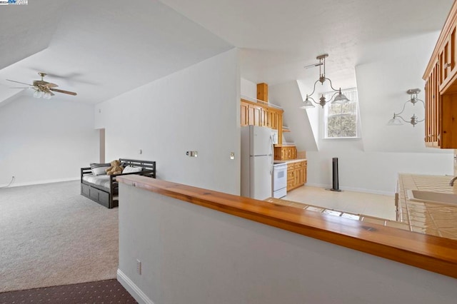 interior space featuring pendant lighting, white appliances, sink, vaulted ceiling, and light colored carpet