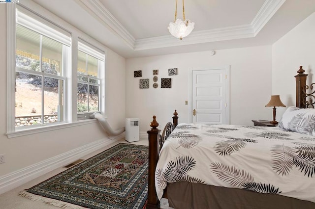 bedroom featuring a tray ceiling, crown molding, and carpet floors