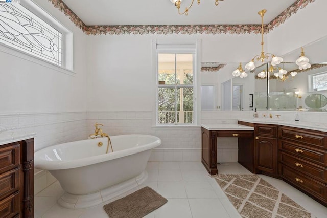 bathroom with vanity, a bath, an inviting chandelier, tile patterned floors, and tile walls