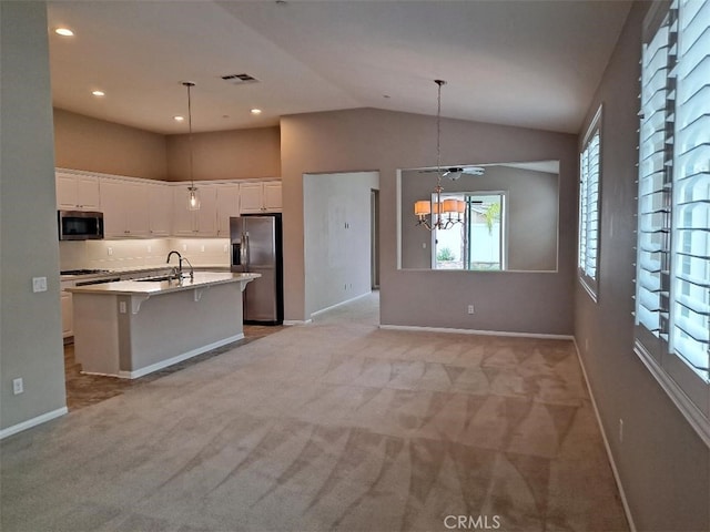 kitchen with a wealth of natural light, an island with sink, stainless steel appliances, and light colored carpet