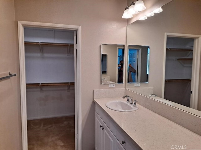 bathroom featuring a walk in closet and vanity