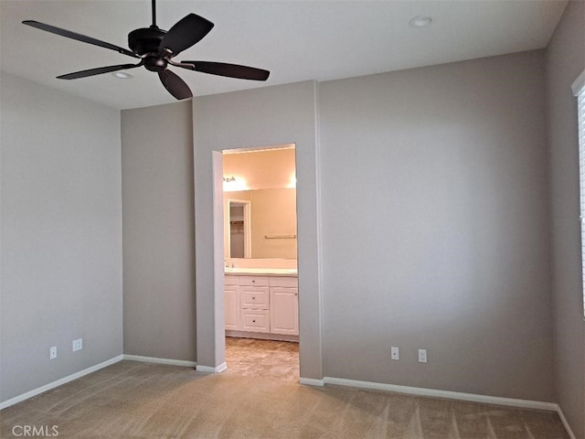 unfurnished bedroom with light carpet, baseboards, and ensuite bathroom