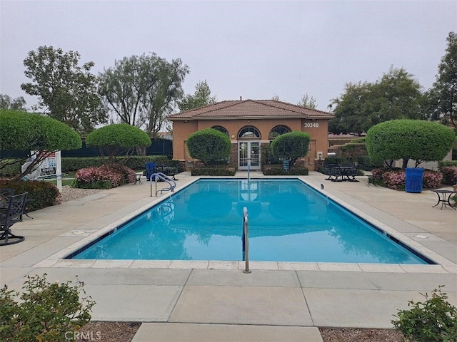 community pool featuring french doors and a patio area