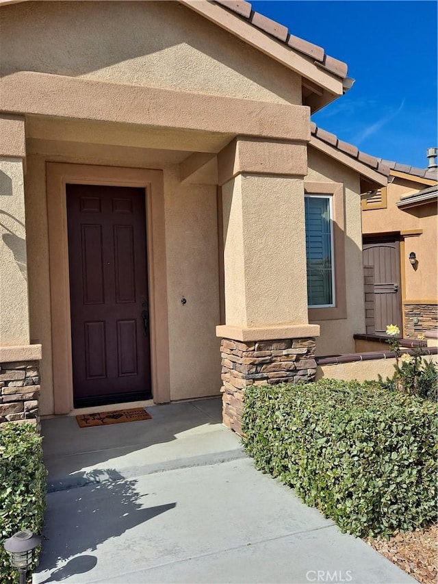 property entrance featuring stone siding and stucco siding