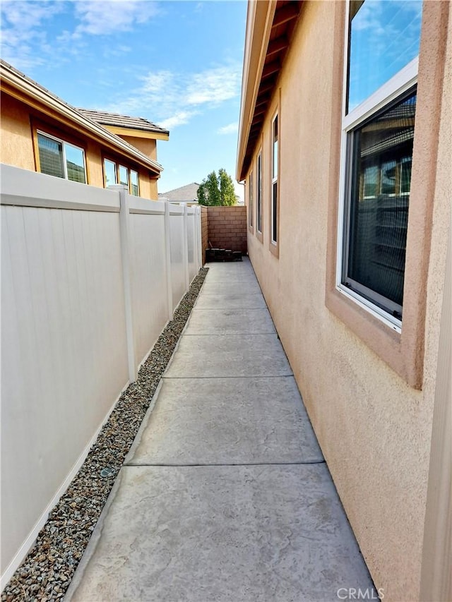 view of side of home with a fenced backyard and stucco siding