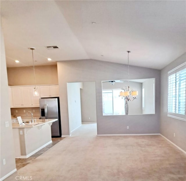 kitchen with decorative light fixtures, light countertops, white cabinetry, a sink, and stainless steel fridge with ice dispenser