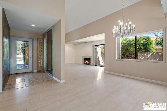 entryway featuring light hardwood / wood-style floors, an inviting chandelier, and a tiled fireplace