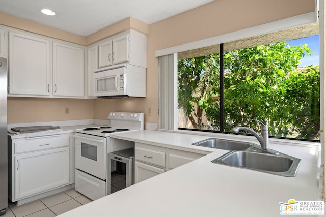 kitchen with white appliances, beverage cooler, sink, white cabinets, and light tile patterned flooring