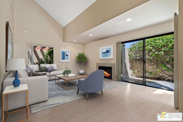 living room with a tile fireplace, hardwood / wood-style flooring, and high vaulted ceiling