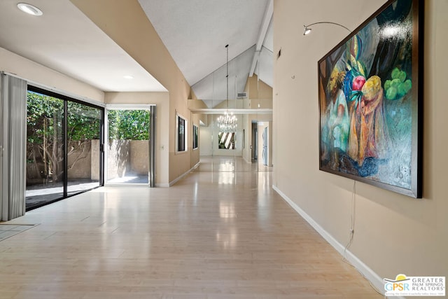 hallway with high vaulted ceiling, a chandelier, and light wood-type flooring