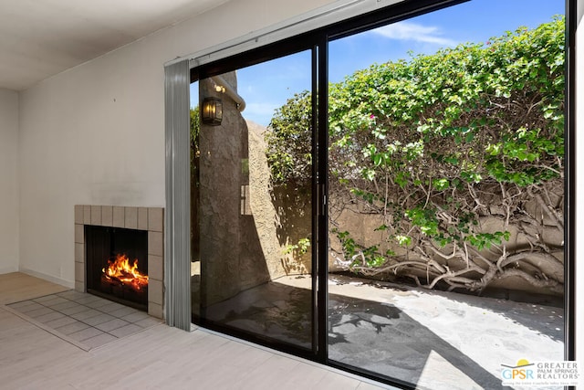 doorway featuring a tile fireplace and light wood-type flooring