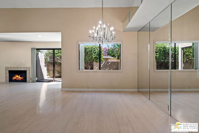 interior space with a tiled fireplace, a towering ceiling, wood-type flooring, and an inviting chandelier