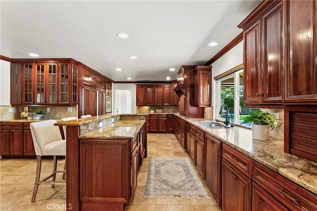 kitchen featuring backsplash, a breakfast bar, crown molding, sink, and a center island