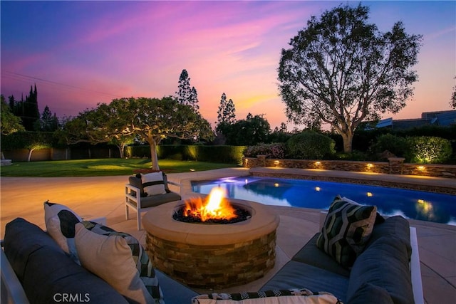 pool at dusk with a fire pit and a patio area