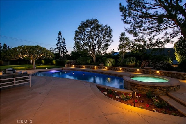 pool at dusk featuring an in ground hot tub and a patio