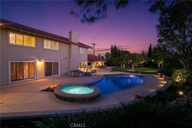 pool at dusk featuring an in ground hot tub, a patio, and an outdoor fire pit