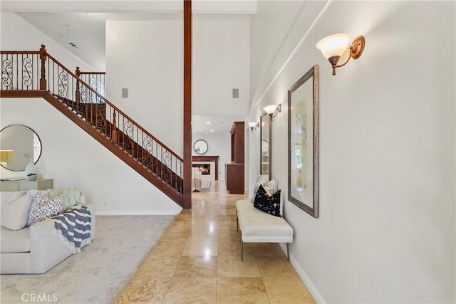 entryway with light colored carpet, crown molding, and a high ceiling