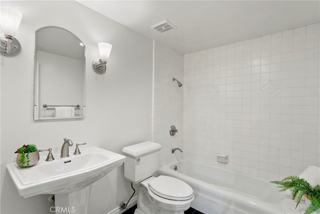 full bathroom with tiled shower / bath combo, toilet, and sink