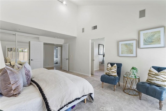 bedroom featuring high vaulted ceiling, ensuite bath, and light colored carpet