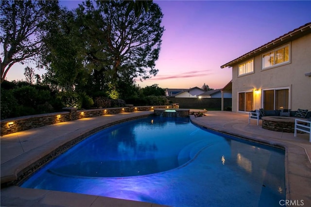 pool at dusk with a patio area, an in ground hot tub, and a fire pit