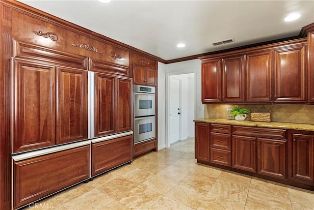 kitchen with double oven, light stone counters, tasteful backsplash, and crown molding