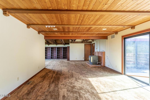 carpeted spare room featuring baseboards, a wood stove, visible vents, beam ceiling, and wood ceiling